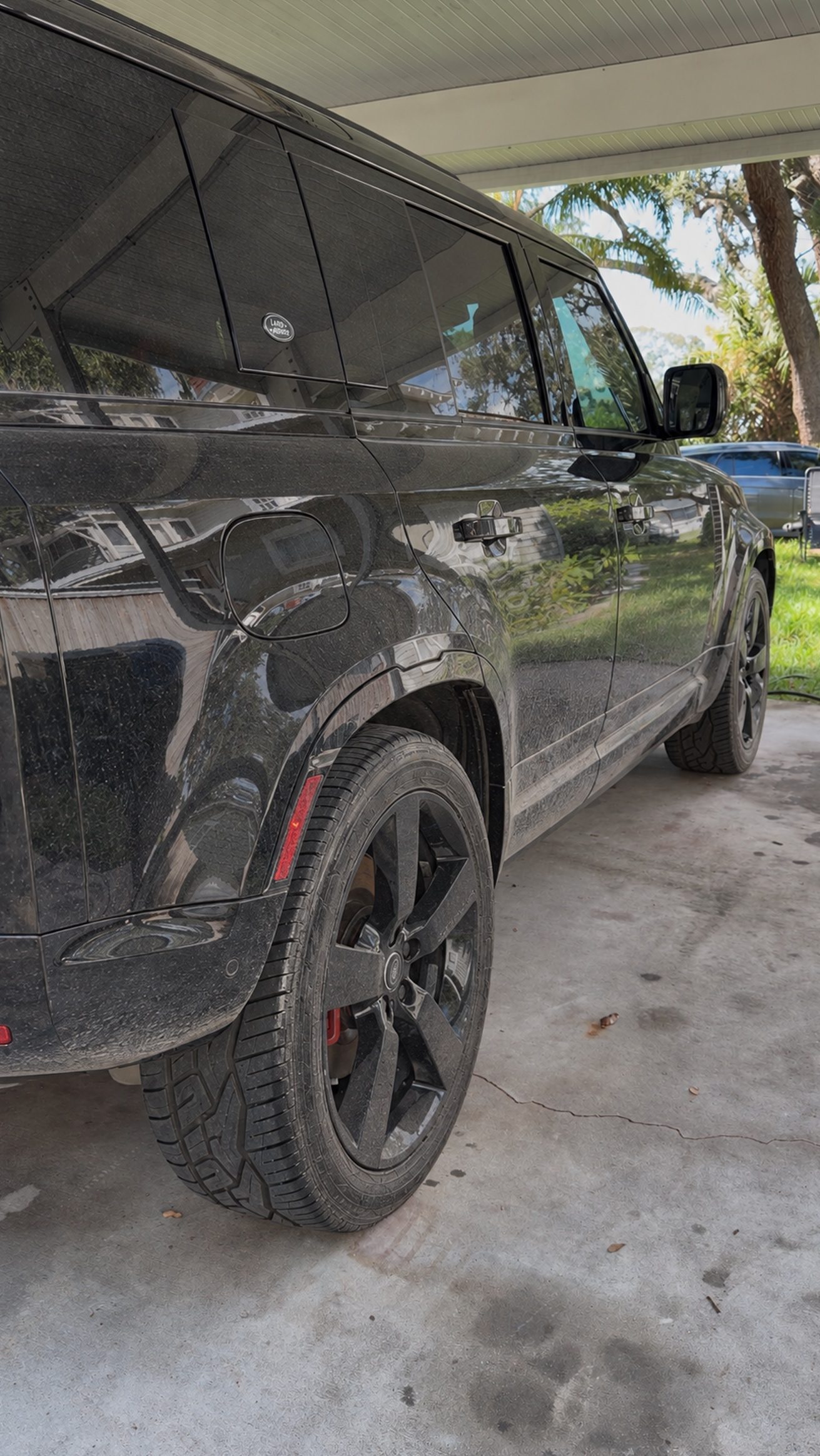 Black Land Rover Defender covered in dust and water spots before detailing